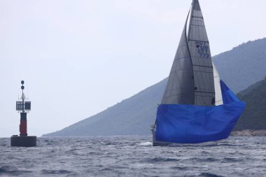 Bodrum, Hindi. 16 Nisan 2023: Yelkenliler Ege Denizi 'nin mavi sularında, ünlü tatil beldesi Bodrum' un kıyılarında rüzgarlı havada yelken açıyor..