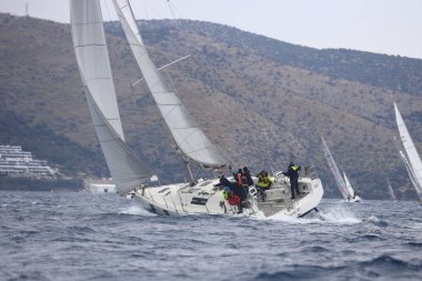 Bodrum, Hindi. 16 Nisan 2023: Yelkenliler Ege Denizi 'nin mavi sularında, ünlü tatil beldesi Bodrum' un kıyılarında rüzgarlı havada yelken açıyor..