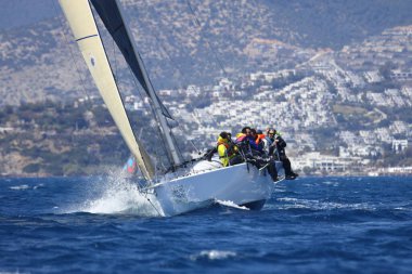 Bodrum, Hindi. 16 Nisan 2023: Yelkenliler Ege Denizi 'nin mavi sularında, ünlü tatil beldesi Bodrum' un kıyılarında rüzgarlı havada yelken açıyor..