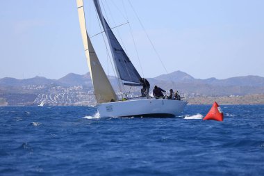 Bodrum, Hindi. 16 Nisan 2023: Yelkenliler Ege Denizi 'nin mavi sularında, ünlü tatil beldesi Bodrum' un kıyılarında rüzgarlı havada yelken açıyor..