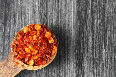 Eski masada ezilmiş kırmızı biberli ahşap kase ve taze kırmızı biber. Seçici odak.