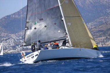 Bodrum, Hindi. 16 Nisan 2023: Yelkenliler Ege Denizi 'nin mavi sularında, ünlü tatil beldesi Bodrum' un kıyılarında rüzgarlı havada yelken açıyor..
