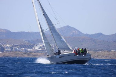 Bodrum, Hindi. 16 Nisan 2023: Yelkenliler Ege Denizi 'nin mavi sularında, ünlü tatil beldesi Bodrum' un kıyılarında rüzgarlı havada yelken açıyor..