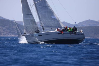 Bodrum, Hindi. 16 Nisan 2023: Yelkenliler Ege Denizi 'nin mavi sularında, ünlü tatil beldesi Bodrum' un kıyılarında rüzgarlı havada yelken açıyor..