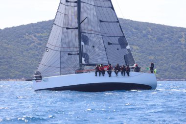 Bodrum, Hindi. 16 Nisan 2023: Yelkenliler Ege Denizi 'nin mavi sularında, ünlü tatil beldesi Bodrum' un kıyılarında rüzgarlı havada yelken açıyor..