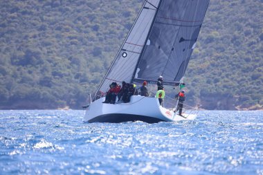 Bodrum, Hindi. 16 Nisan 2023: Yelkenliler Ege Denizi 'nin mavi sularında, ünlü tatil beldesi Bodrum' un kıyılarında rüzgarlı havada yelken açıyor..