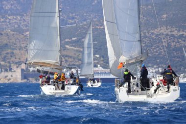 Bodrum, Hindi. 16 Nisan 2023: Yelkenliler Ege Denizi 'nin mavi sularında, ünlü tatil beldesi Bodrum' un kıyılarında rüzgarlı havada yelken açıyor..