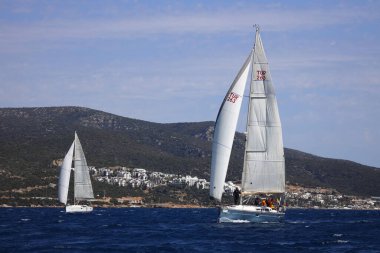 Bodrum, Hindi. 16 Nisan 2023: Yelkenliler Ege Denizi 'nin mavi sularında, ünlü tatil beldesi Bodrum' un kıyılarında rüzgarlı havada yelken açıyor..