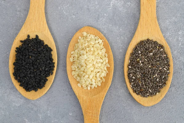 stock image Wooden scoops with chia, black cumin and white sesame seeds close-up. Selective Focus.