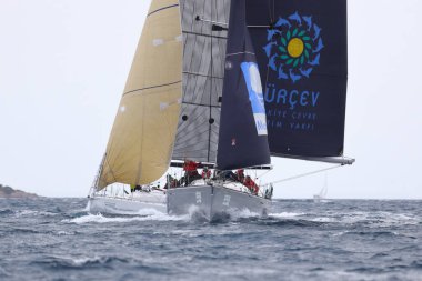 Bodrum, Hindi. 02 Nisan 2023: Ege Denizi 'nin mavi sularında, ünlü tatil beldesi Bodrum' un kıyılarında yelkenliler rüzgarlı havada yelken açıyor.