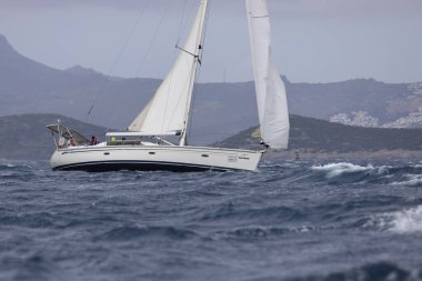 Bodrum, Hindi. 02 Nisan 2023: Ege Denizi 'nin mavi sularında, ünlü tatil beldesi Bodrum' un kıyılarında yelkenliler rüzgarlı havada yelken açıyor.