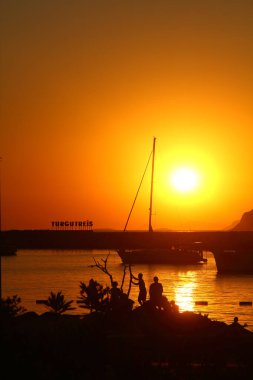 Bodrum, Mugla, Türkiye. 07 Temmuz 2020. Gün ışığında deniz manzarası. Deniz feneri ve sahilde yelkenliler. Deniz kenti Turgutreis ve muhteşem güneş ışığı