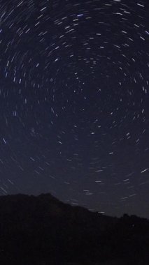 Önünde bir dağ tepesi olan Samanyolu 'nun yıldızlarının görüntüsü. Gece gökyüzü doğa yaz manzarası. Perseid Meteor yağmuru gözlemi. Sosyal medya için dikey video.