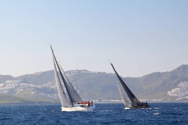 Bodrum, Hindi. 23 Mart 2019: Yelkenliler Ege Denizi 'nin mavi sularında, ünlü tatil beldesi Bodrum' un kıyılarında rüzgarlı havada yelken açıyorlar..