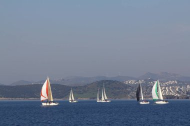 Bodrum, Hindi. 18 Ocak 2020: Yelkenliler Ege Denizi 'nin mavi sularında, ünlü tatil beldesi Bodrum' un kıyılarında rüzgarlı havada yelken açıyor..