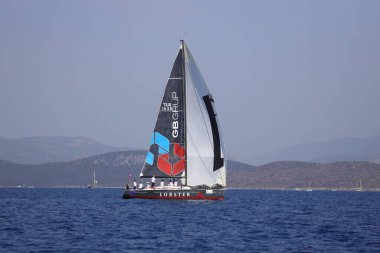 Bodrum, Hindi. 07 Ekim 2023: Ege Denizi 'nin mavi sularında, ünlü tatil beldesi Bodrum' un kıyılarında yelkenliler rüzgarlı havada yelken açıyor.