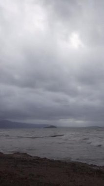 Denizin üzerinde fırtına bulutları. Fırtınadan önce güneş ışığı hareketi. Deniz kenti Turgutreis ve muhteşem gün batımları. Sosyal medya için dikey video.