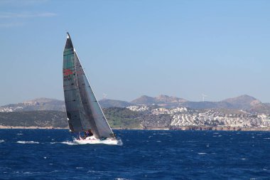 Bodrum, Hindi. 01 Mart 2020: Yelkenliler Ege Denizi 'nin mavi sularında, ünlü tatil beldesi Bodrum' un kıyılarında rüzgarlı havada yelken açıyor..