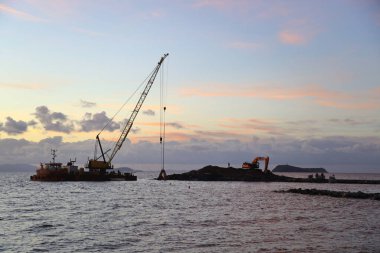 Bodrum, Mugla, Türkiye. 01 Aralık 2023: Devasa vinçlerin siluetleri kanlı bir günbatımına karşı nakil limanında