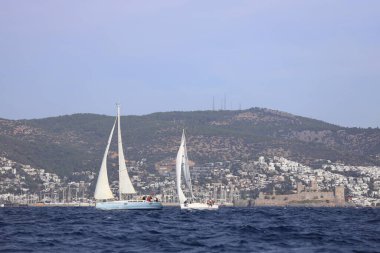 Bodrum, Hindi. 02 Aralık 2023: Yelkenliler Ege Denizi 'nin mavi sularında, ünlü tatil beldesi Bodrum' un kıyılarında rüzgarlı havada yelken açıyorlar..
