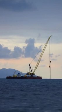 Gün batımında açık deniz tamir platformu. Turna borusunu denize yerleştiriyorum. Sosyal medya için dikey video.