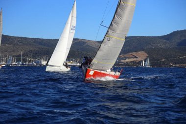 Bodrum, Hindi. 14 Ocak 2024: Yelkenliler Ege Denizi 'nin mavi sularında, ünlü tatil beldesi Bodrum' un kıyılarında rüzgarlı havada yelken açıyorlar..