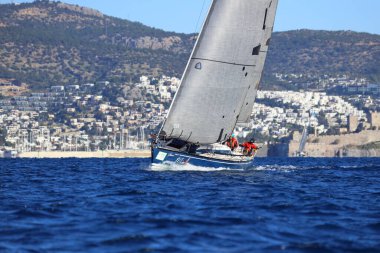 Bodrum, Hindi. 14 Ocak 2024: Yelkenliler Ege Denizi 'nin mavi sularında, ünlü tatil beldesi Bodrum' un kıyılarında rüzgarlı havada yelken açıyorlar..
