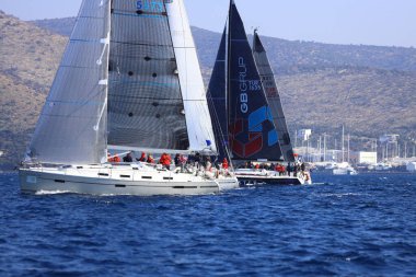 Bodrum, Hindi. 03 Şubat 2024: Ege Denizi 'nin mavi sularında, ünlü tatil beldesi Bodrum' un kıyılarında yelkenliler rüzgarlı havada yelken açıyor.