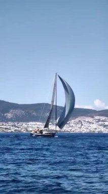 Bodrum, Hindi. 23 Şubat 2024: Yelkenliler Ege Denizi 'nin mavi sularında, ünlü tatil beldesi Bodrum' un kıyılarında rüzgarlı havada yelken açıyorlar. Sosyal medya için dikey video. 