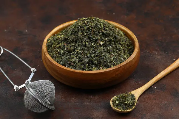 Green tea with herbs in wooden bowl on a wooden board