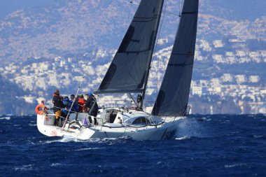 Bodrum, Hindi. 03 Şubat 2024: Ege Denizi 'nin mavi sularında, ünlü tatil beldesi Bodrum' un kıyılarında yelkenliler rüzgarlı havada yelken açıyor.