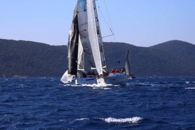 Bodrum, Hindi. 03 Şubat 2024: Ege Denizi 'nin mavi sularında, ünlü tatil beldesi Bodrum' un kıyılarında yelkenliler rüzgarlı havada yelken açıyor.