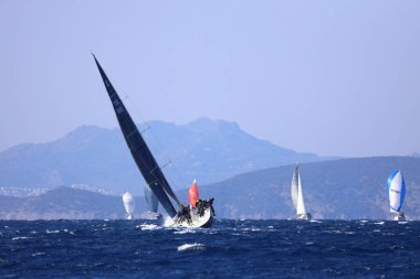 Bodrum, Hindi. 03 Şubat 2024: Ege Denizi 'nin mavi sularında, ünlü tatil beldesi Bodrum' un kıyılarında yelkenliler rüzgarlı havada yelken açıyor.