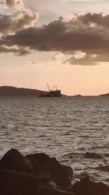 Denizde balıkçı teknesi. Denizin üzerinde deniz manzaralı altın gün doğumu. Gündoğumunda tekne. Güzel bir balıkçı teknesi olan deniz manzarası. Dikey video.