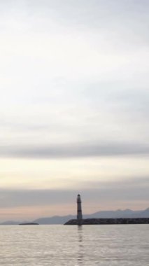 Gün batımında deniz manzarası. Sahildeki deniz feneri. Deniz kenti Turgutreis ve muhteşem gün batımı. Sosyal medya için dikey video.