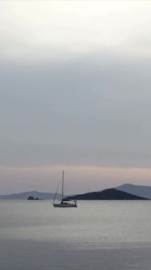 Günbatımında yalnız yelkenli. Atmosferik deniz manzarası. Sosyal medya için dikey video.