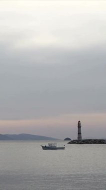 Gün batımında deniz manzarası. Sahildeki deniz feneri. Deniz kenti Turgutreis ve muhteşem gün batımı. Sosyal medya için dikey video.