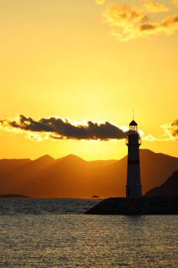 Gün ışığında deniz manzarası. Deniz feneri ve sahilde yelkenliler. Deniz kenti Turgutreis ve muhteşem güneş ışığı
