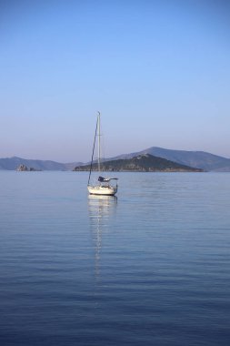 Günbatımında yalnız yelkenliler. Yansımalı atmosferik deniz manzarası