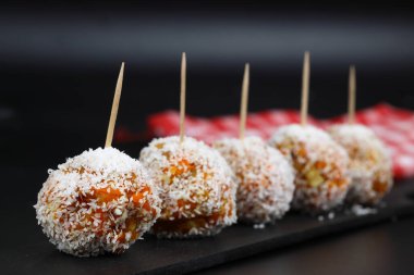 Siyah bir arka planda siyah bir tabakta hindistan cevizli güzel tatlılar.