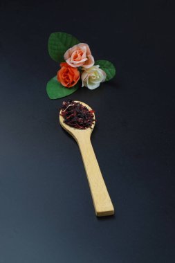 Karkade tea. Hibiscus tea leaves in wooden spoon isolated on wooden background. File contains clipping path. Top view. Selective focus. clipart