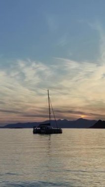 Denizde yelkenli. Denizin üzerinde deniz manzaralı altın gün doğumu. Gündoğumunda yat gezintisi. Güzel bir yelkenli ile deniz manzarası. Yelkenliyle turizm turizmi yapıyor. Dikey video.