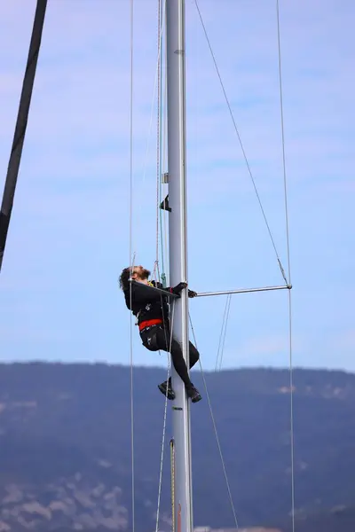 stock image Bodrum,Turkey. 25 February 2024: Young man hanging and repairs yacht mast High Up Stock Photo