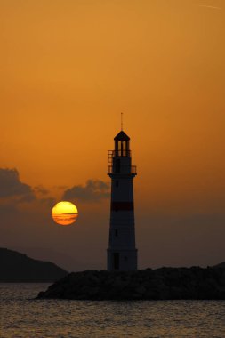 Gün ışığında deniz manzarası. Deniz feneri ve sahilde yelkenliler. Deniz kenti Turgutreis ve muhteşem güneş ışığı