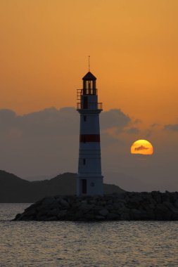 Gün ışığında deniz manzarası. Deniz feneri ve sahilde yelkenliler. Deniz kenti Turgutreis ve muhteşem güneş ışığı