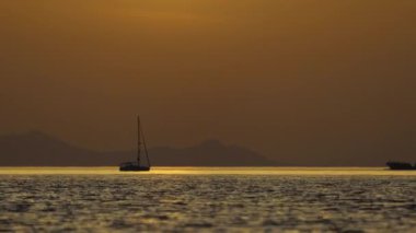 Denizde yelkenli. Denizin üzerinde deniz manzaralı altın gün doğumu. Gündoğumunda yat gezintisi. Güzel bir yelkenli ile deniz manzarası. Yelkenliyle turizm turizmi.