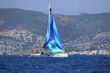 Bodrum, Hindi. 28 Nisan 2024: Yelkenliler Ege Denizi 'nin mavi sularında, ünlü tatil beldesi Bodrum' un kıyılarında rüzgarlı havada yelken açıyorlar..