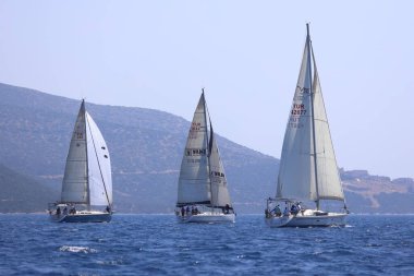 Bodrum, Hindi. 28 Nisan 2024: Yelkenliler Ege Denizi 'nin mavi sularında, ünlü tatil beldesi Bodrum' un kıyılarında rüzgarlı havada yelken açıyorlar..