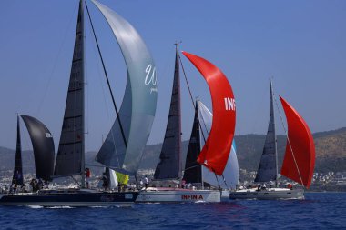 Bodrum, Hindi. 28 Nisan 2024: Yelkenliler Ege Denizi 'nin mavi sularında, ünlü tatil beldesi Bodrum' un kıyılarında rüzgarlı havada yelken açıyorlar..