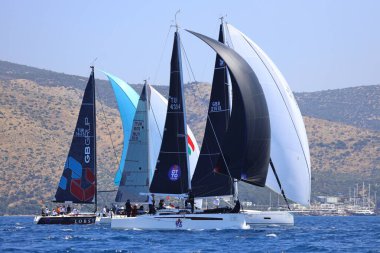 Bodrum, Hindi. 28 Nisan 2024: Yelkenliler Ege Denizi 'nin mavi sularında, ünlü tatil beldesi Bodrum' un kıyılarında rüzgarlı havada yelken açıyorlar..